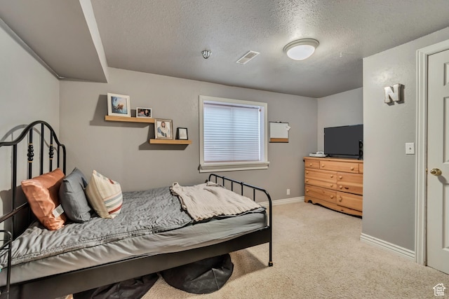 bedroom featuring light colored carpet, a textured ceiling, and baseboards