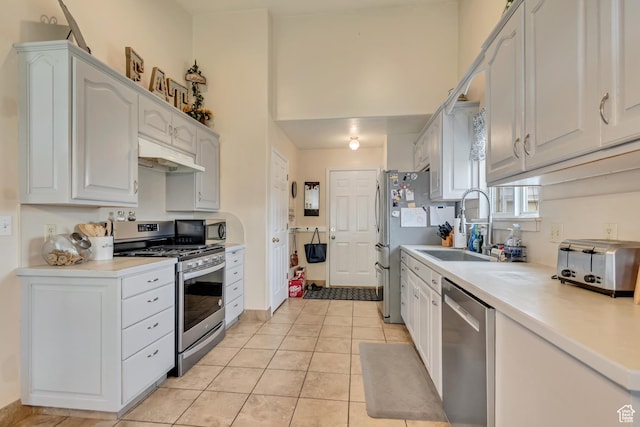 kitchen featuring appliances with stainless steel finishes, under cabinet range hood, light tile patterned floors, light countertops, and white cabinets