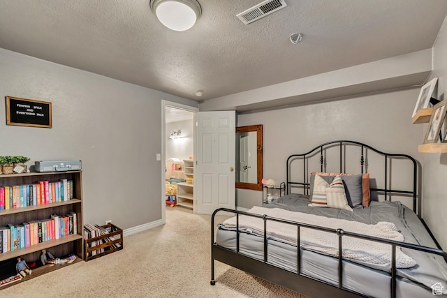 carpeted bedroom with a textured ceiling and baseboards