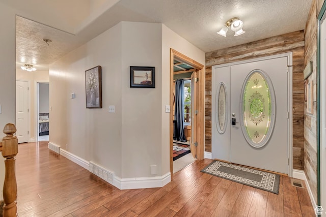 entrance foyer featuring a textured ceiling, light wood-type flooring, and baseboards