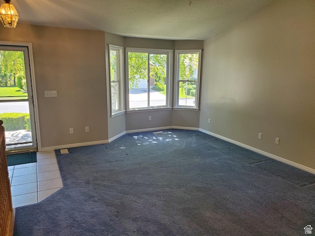 carpeted empty room with baseboards and a chandelier