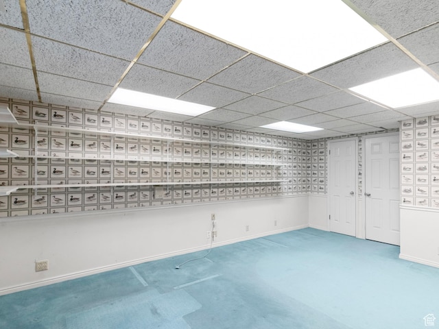 unfurnished room with a drop ceiling, baseboards, and carpet