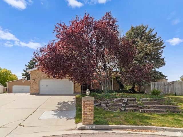 obstructed view of property with fence, driveway, brick siding, and an attached garage