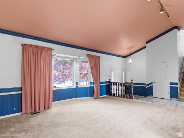 empty room with lofted ceiling, carpet floors, crown molding, stairway, and baseboards
