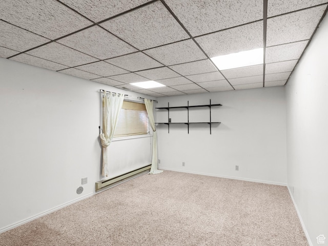 basement with baseboard heating, carpet flooring, baseboards, and a drop ceiling
