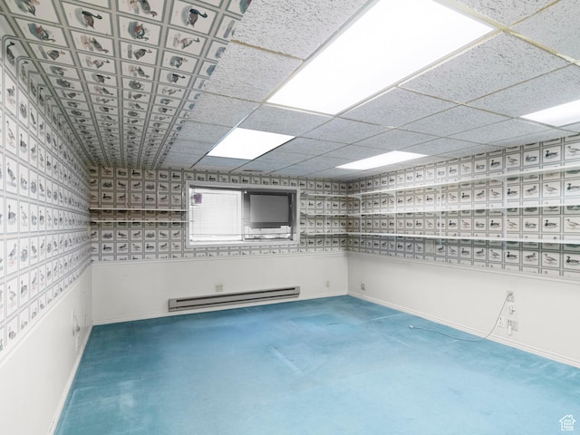 carpeted spare room featuring a baseboard heating unit and baseboards