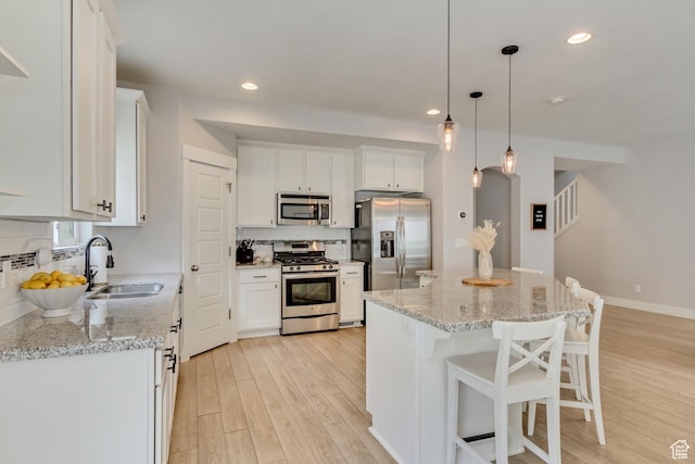 238 E Hillcrest Way N, Salt Lake, UT 84054 - kitchen with appliances with stainless steel finishes, a sink, light wood finished floors, decorative backsplash, and white cabinetry