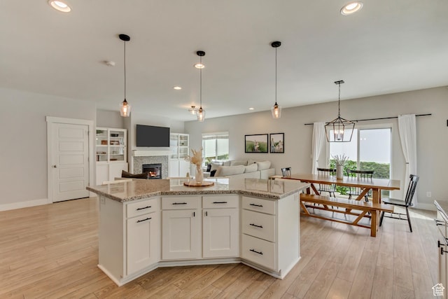 238 E Hillcrest Way N, Salt Lake, UT 84054 - kitchen featuring recessed lighting, a lit fireplace, light wood-style flooring, light stone countertops, and baseboards