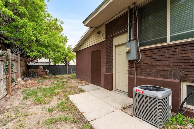view of home's exterior with brick siding, fence, and central AC