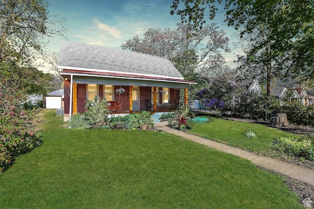 view of front of house featuring covered porch, a front yard, and brick siding
