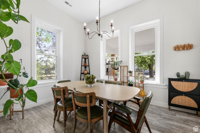 dining area featuring plenty of natural light, light wood-style flooring, and a chandelier