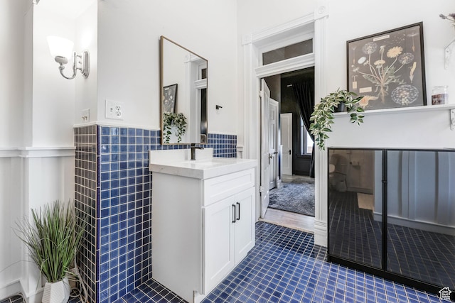 bathroom featuring a wainscoted wall, tile patterned flooring, vanity, and tile walls