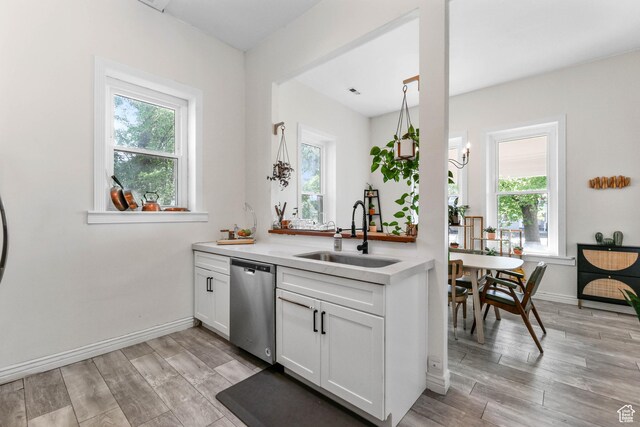 kitchen with a sink, dishwasher, light countertops, white cabinetry, and light wood-style flooring