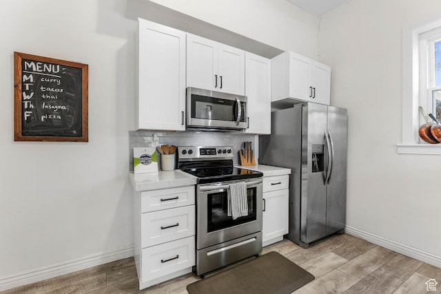 kitchen featuring appliances with stainless steel finishes, light wood-style flooring, light countertops, and white cabinets