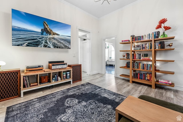 living area with crown molding, wood finished floors, and baseboards