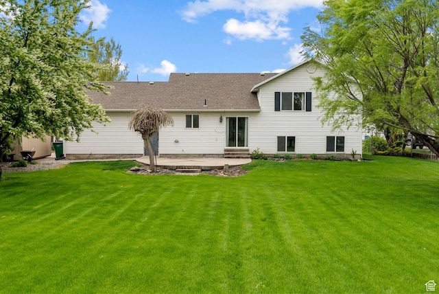 rear view of property with a patio, a yard, and a shingled roof
