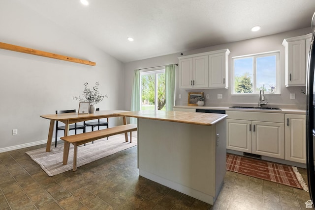 kitchen with a sink, light countertops, white cabinets, recessed lighting, and a center island