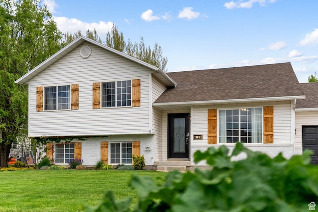 split level home with a front yard and a shingled roof