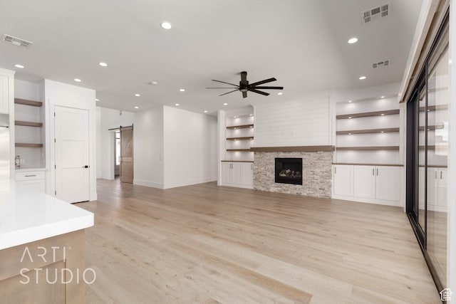2832 E Stonedale Dr, St George, UT 84790 - unfurnished living room featuring a barn door, light wood-style flooring, ceiling fan, built in features, and recessed lighting