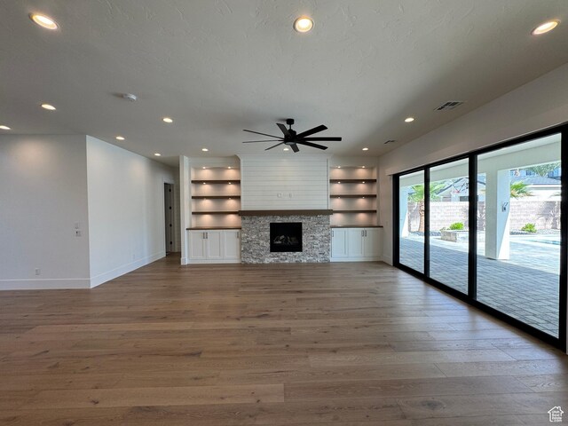 unfurnished living room featuring wood finished floors, baseboards, ceiling fan, recessed lighting, and built in features