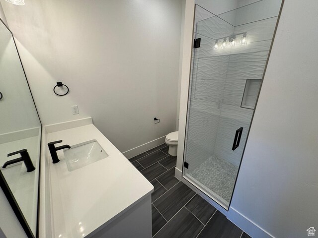 full bathroom with a shower stall, baseboards, toilet, and vanity