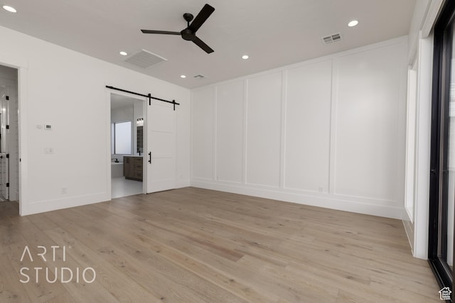 2832 E Stonedale Dr, St George, UT 84790 - unfurnished bedroom with a barn door, a decorative wall, light wood-style flooring, recessed lighting, and ensuite bathroom