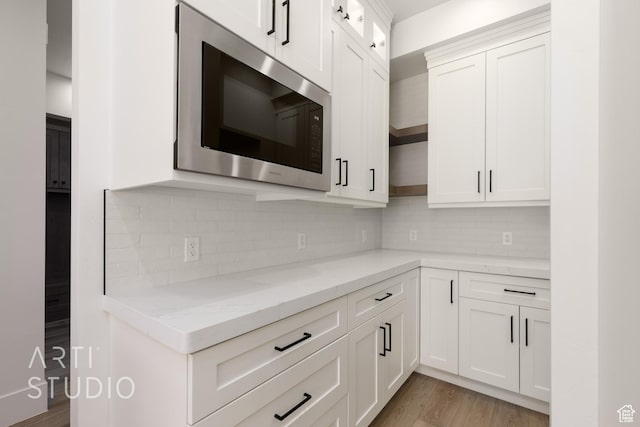 2832 E Stonedale Dr, St George, UT 84790 - kitchen with stainless steel microwave, light stone counters, white cabinetry, light wood-style floors, and backsplash