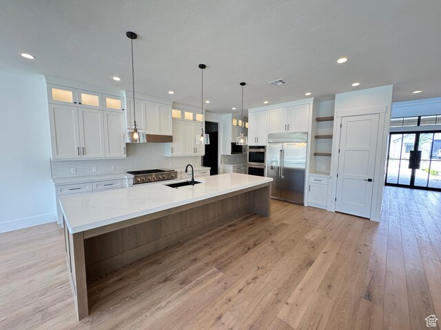 kitchen featuring stainless steel appliances, a sink, open shelves, white cabinets, and light wood-style floors