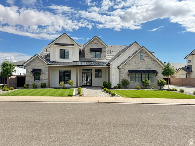 view of front facade featuring a standing seam roof, board and batten siding, covered porch, and stone siding
