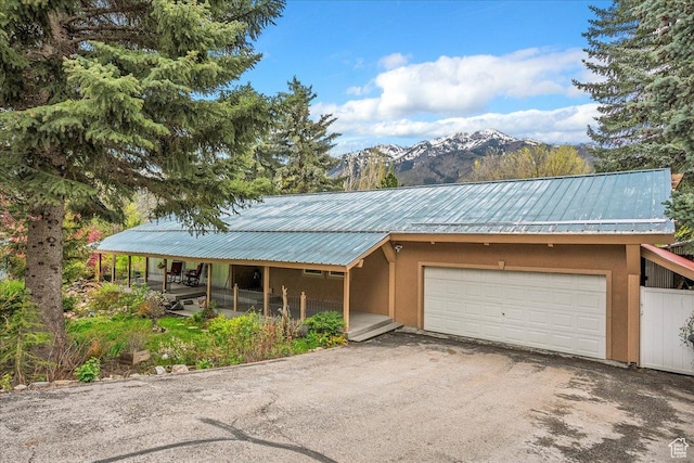 5925 W Highland Dr N, Mountain Green, UT 84050 - view of front of property featuring a garage, a mountain view, asphalt driveway, metal roof, and stucco siding
