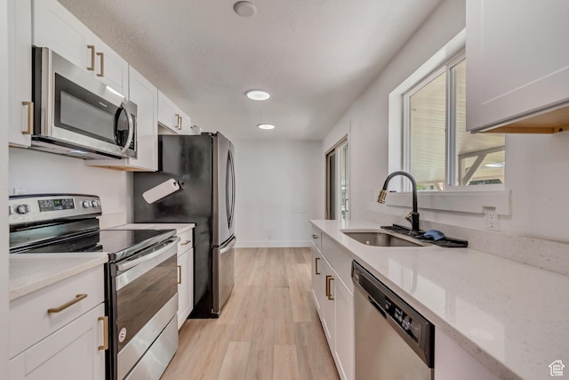 172 E 400 N, Tooele, UT 84074 - kitchen featuring stainless steel appliances, a sink, light wood-style flooring, white cabinets, and light stone countertops