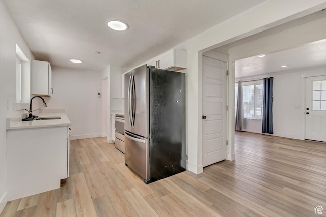 172 E 400 N, Tooele, UT 84074 - kitchen featuring appliances with stainless steel finishes, a sink, light countertops, light wood finished floors, and white cabinets