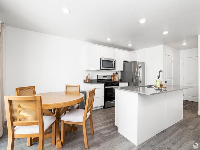 944 E Jack Dr, Saratoga Springs, UT 84045 - kitchen with appliances with stainless steel finishes, wood finished floors, a kitchen island with sink, white cabinetry, and recessed lighting
