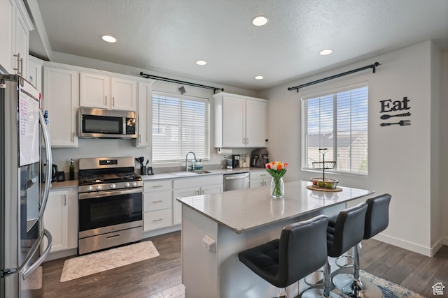 kitchen with stainless steel appliances, a sink, a breakfast bar, plenty of natural light, and recessed lighting