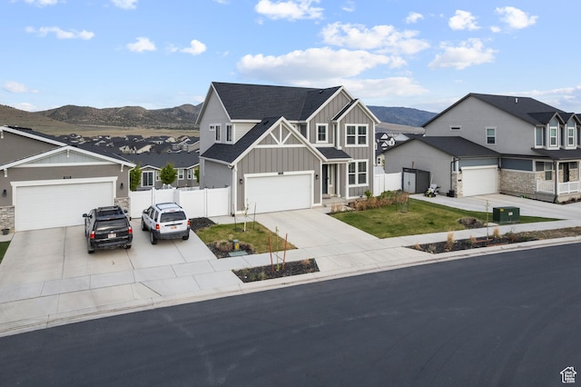 view of front of house featuring board and batten siding, a residential view, fence, a mountain view, and driveway