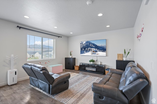 living room featuring wood finished floors, recessed lighting, a textured ceiling, and baseboards