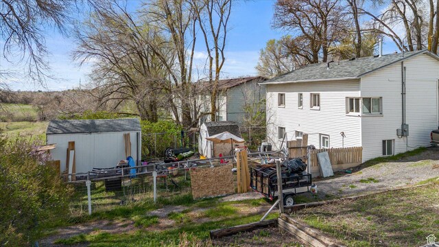 rear view of house featuring a storage shed, an outdoor structure, and fence