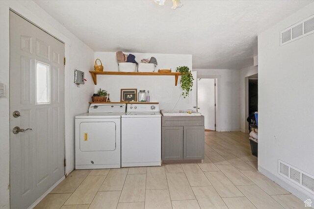 clothes washing area featuring cabinet space and independent washer and dryer