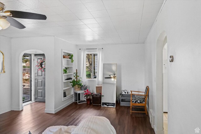 living room with arched walkways, a ceiling fan, and wood finished floors