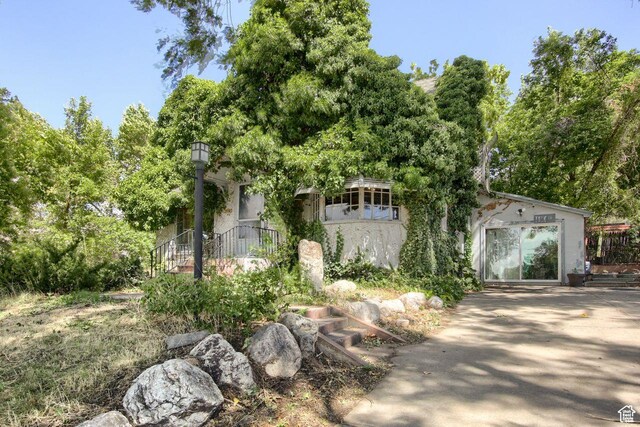 view of property hidden behind natural elements with stucco siding