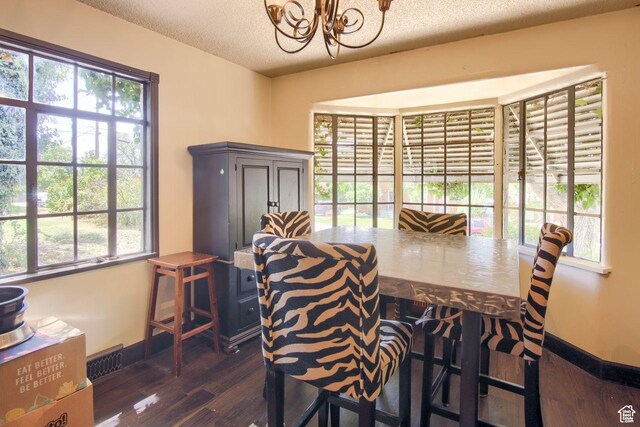 dining room featuring dark wood finished floors, a chandelier, a textured ceiling, and baseboards