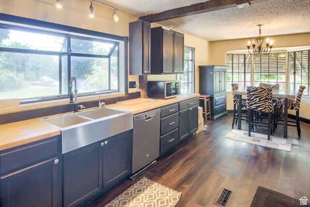 kitchen featuring appliances with stainless steel finishes, a textured ceiling, a sink, a chandelier, and dark wood-style floors