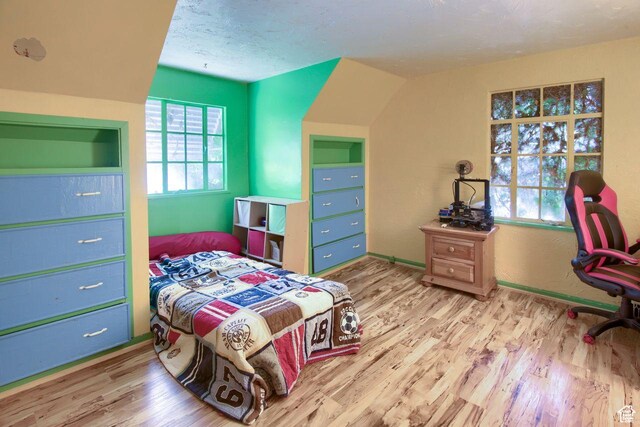 bedroom featuring wood finished floors, baseboards, and a textured ceiling