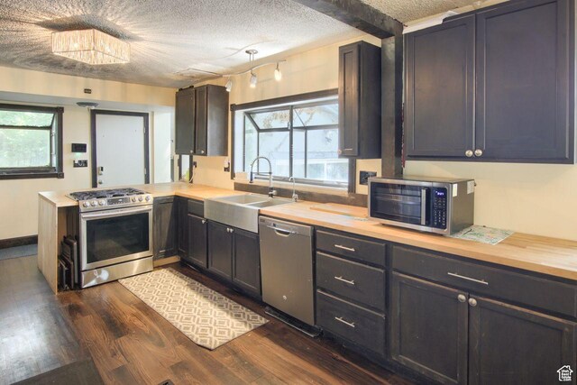 kitchen with stainless steel appliances, a sink, dark wood-style floors, a peninsula, and a textured ceiling
