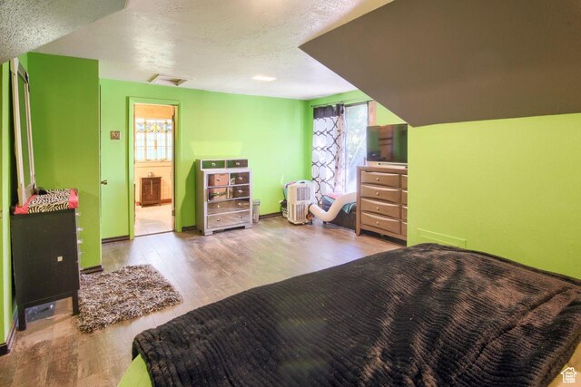 bedroom with hardwood / wood-style floors, multiple windows, a textured ceiling, and baseboards