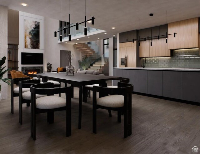 dining area with stairway, dark wood-style flooring, a warm lit fireplace, and recessed lighting