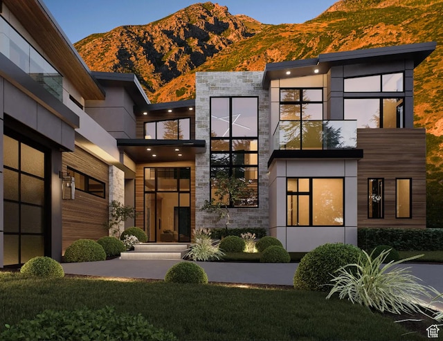 view of front of property with a mountain view, stone siding, and a front yard