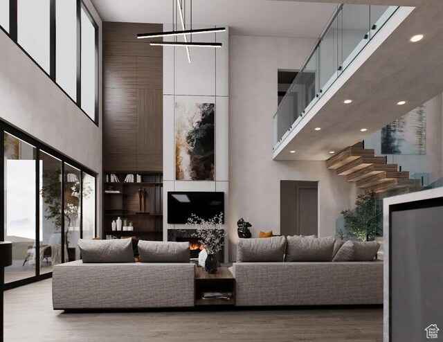 living area with a high ceiling, plenty of natural light, wood finished floors, recessed lighting, and a chandelier
