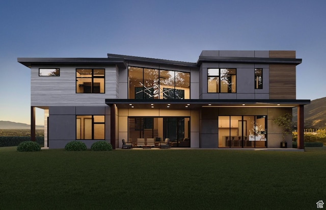 back of house featuring a balcony and a yard