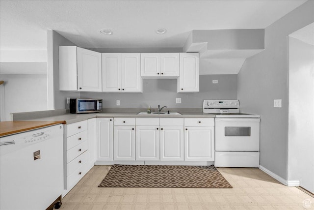 kitchen featuring white appliances, a sink, light flooring, baseboards, and recessed lighting